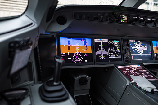 The side stick and large screens in a modern airliner cockpit.