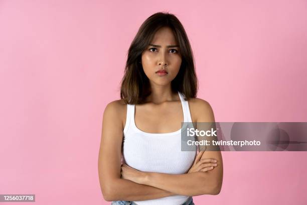 Portrait Of Young Woman With Arms Folded Against Pink Background Stock Photo - Download Image Now