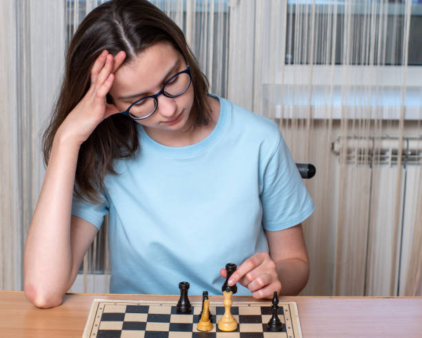 istock Caucasian girl with glasses thinking playing chess, playing chess at home during quarantine 1256042007
