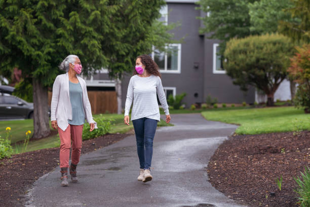 istock Two women wearing protective face masks while going for a walk during Coronavirus 1256048302