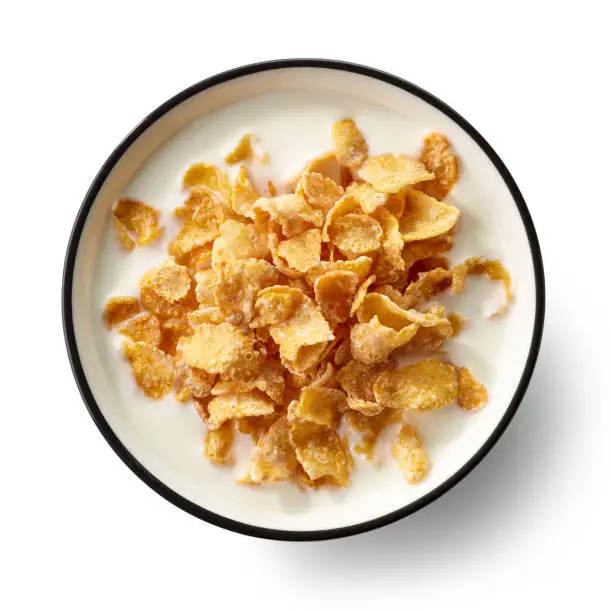 bowl of sweet cornflakes with milk isolated on white background, top view