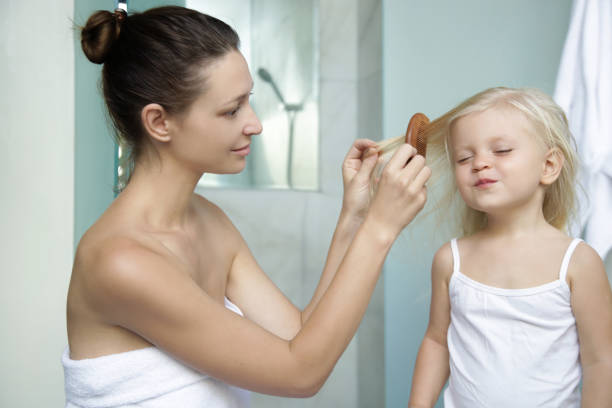istock Mother brushing her little daughter's hair in bathroom 1256055191