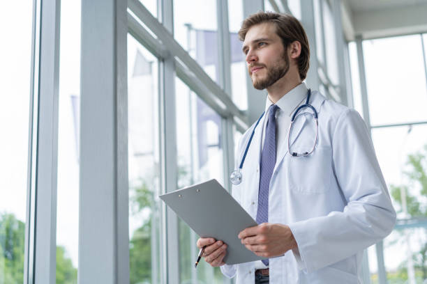 istock Male Doctor standing with folder in hospital. 1256055405