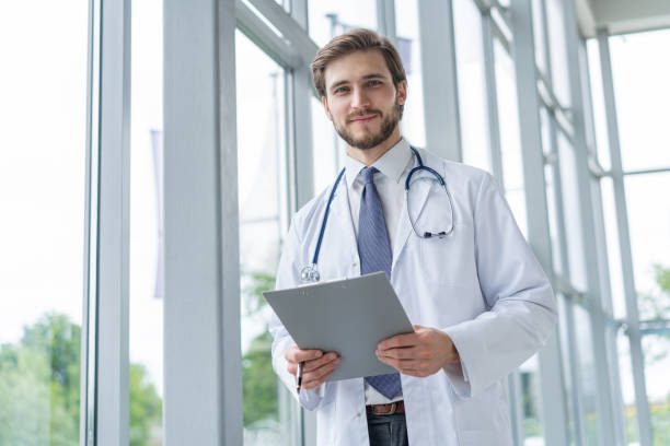 istock Male Doctor standing with folder in hospital. 1256055411