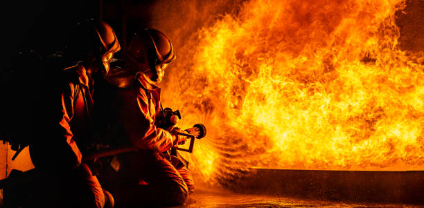 Firefighters use twirl water fog spraying down fire flame. Panoramic firefighters using Twirl water fog type fire extinguisher to fighting with the fire flame from oil to control fire not to spreading out. Firefighter and industrial safety concept. hose photos stock pictures, royalty-free photos & images