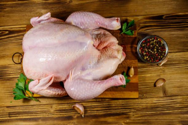 istock Raw whole chicken with spices on a wooden table. Top view 1256062705