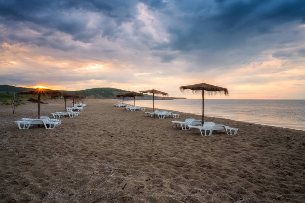 istock Straw sunshades and sunbeds on the empty sandy beach 1256064108