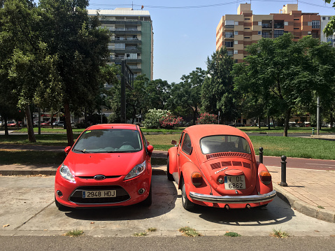 Valencia, Spain - July 12, 2020: Two compact cars, one modern and the other vintage parked in the street. It is hard to see cars this old moving around the city