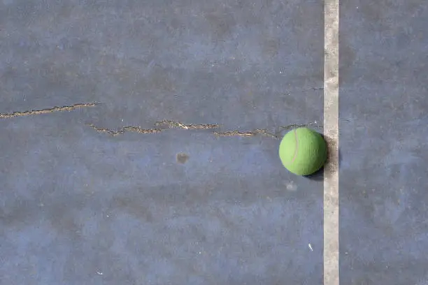 Old tennisball on a blue rundown tennis court