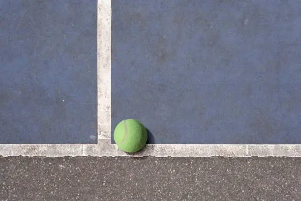 Old tennisball on a blue rundown tennis court