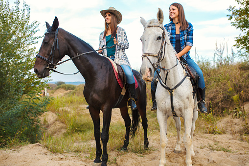 Two young women enjoy riding horses in nature