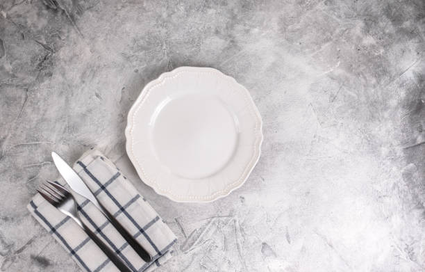 istock Empty white plate with cutlery on a gray background. Mock up 1256078239
