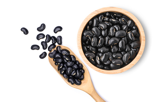Black beans (Urad dal, black gram, vigna mungo ) in wooden bowl and scoop isolated on white background .