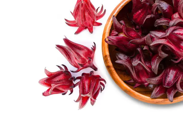 Close-up fresh red  Roselle fruit ( Jamaica sorrel, Rozelle or hibiscus sabdariffa ) in wooden bowl isolated on white background. Top view. Flat lay.