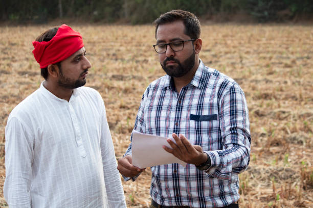 Salesman explaining contract farming agreement to farmer on field