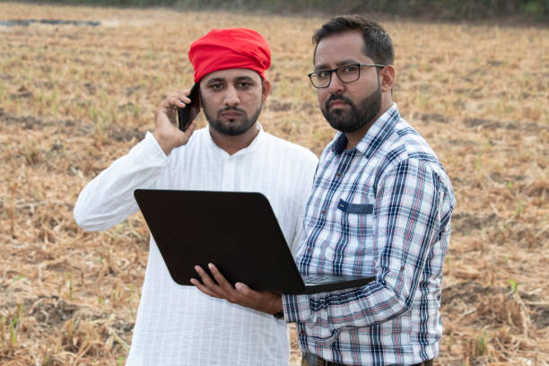 istock Farmer with businessman using laptop and talking on mobile phone 1256084563