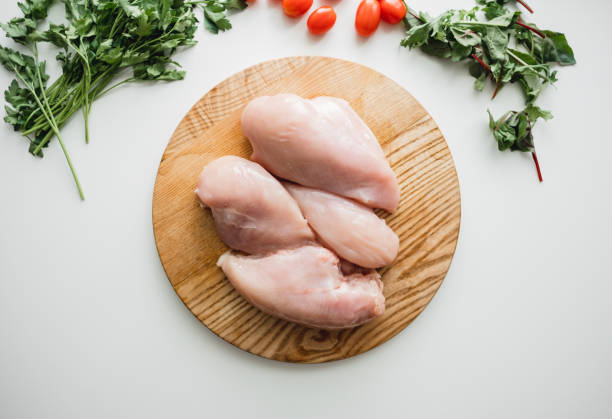 istock Chicken fillet on a wooden board with herbs, white background. 1256085096