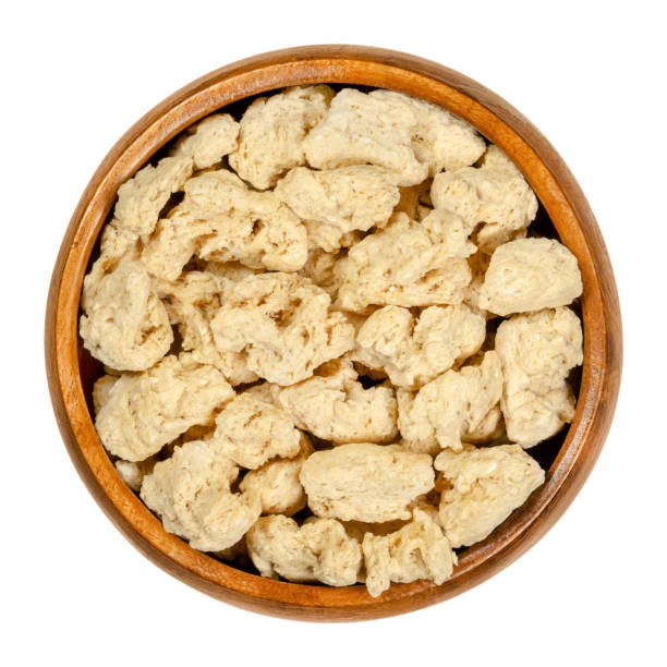 Soya chunks, textured soy protein, soy meat in wooden bowl Soya chunks in wooden bowl. Textured soy protein, also known as soy meat. Defatted soy flour product, used as meat analogue or meat extender. Closeup from above, over white, isolated macro food photo. tsp stock pictures, royalty-free photos & images