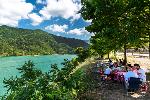 Kocaeli, Turkey - July 05, 2020: People having a picnic under trees by the lake during the weekend break. Yuvacik dam lake and nature in Kocaeli province, Turkey.