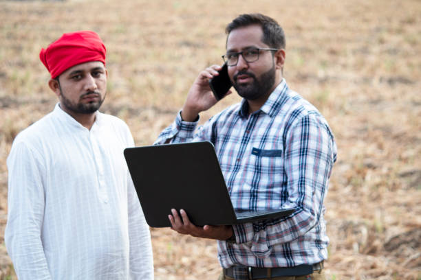 istock Farmer with businessman using laptop and talking on mobile phone 1256093008