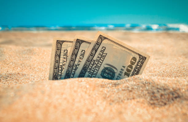 dolars d’argent à moitié couverts de sable se trouvent sur la plage de sable près de l’océan de mer - 300 photos et images de collection