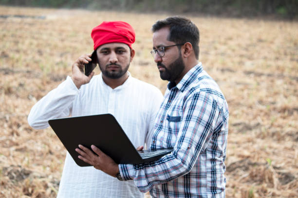 istock Farmer with businessman using laptop and talking on mobile phone 1256096794