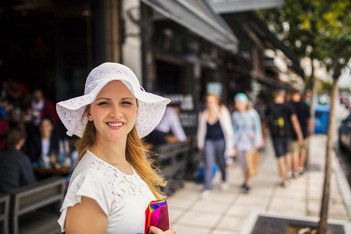Beautiful woman with white hat on city street
