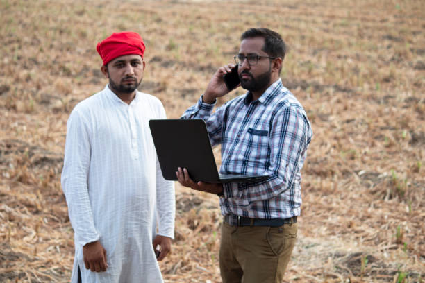 istock Farmer with businessman using laptop and talking on mobile phone 1256097516