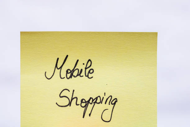 istock Mobile shopping handwriting text close up isolated on yellow paper with copy space. 1256097596