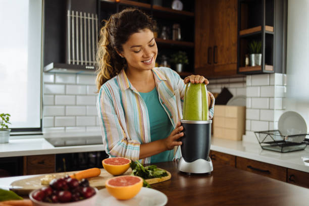 istock Young woman preparing a green smoothie at home 1256097741