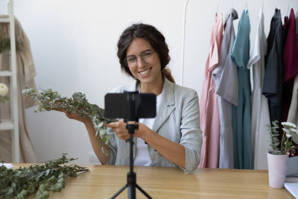 istock Smiling female florist shoot video tutorial on cellphone 1256097805