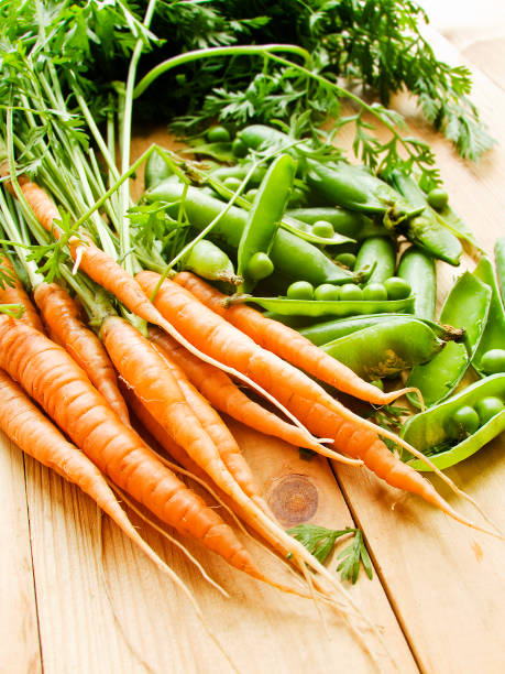 istock Fresh baby carrots and green peas 1256097961