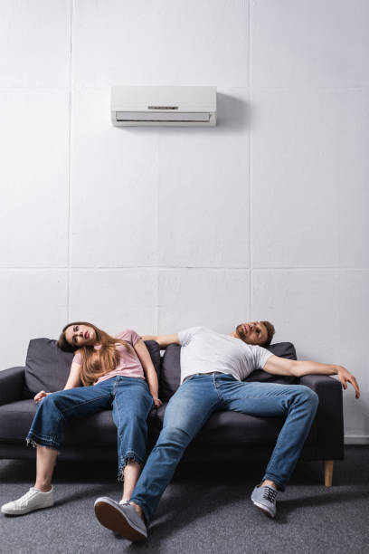istock exhausted couple suffering from heat while sitting home with broken air conditioner 1256098096