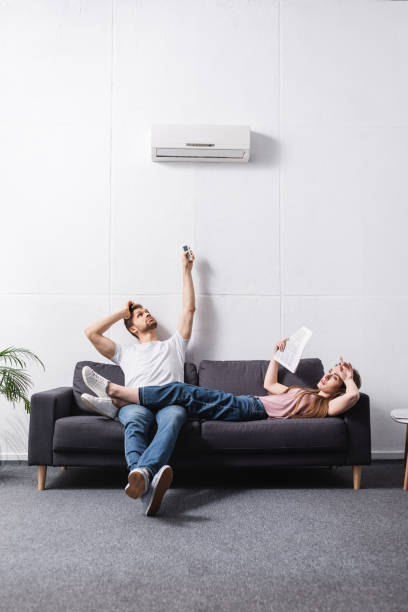 istock young tired couple with remote controller suffering from heat at home with broken air conditioner 1256098104