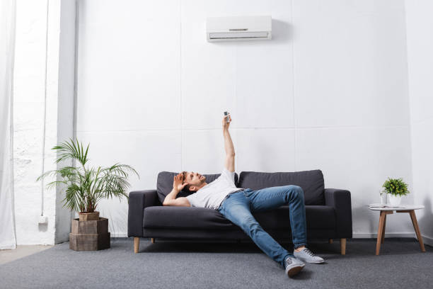 istock exhausted man holding remote controller and suffering from heat with broken air conditioner at home 1256098112