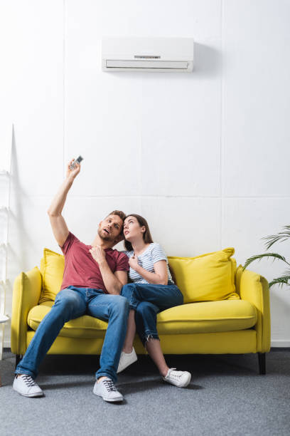 istock confused couple with remote controller suffering from heat at home with broken air conditioner 1256098122