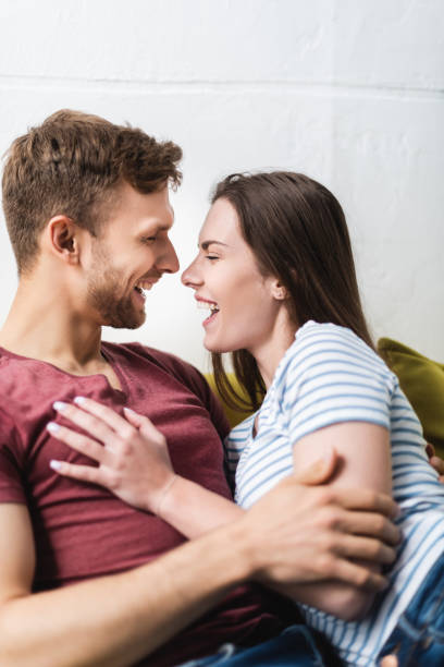 istock laughing beautiful young couple hugging at home 1256098124