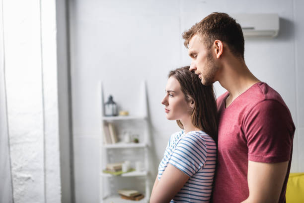 istock sad beautiful young couple hugging at home 1256098133