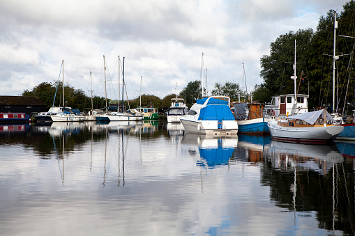 Moored boats on Blackwater canal Essex early morning with reflection in water