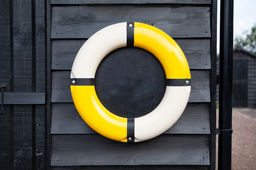 Yellow and white ring buoy for use as a menu on side of black wooden shed