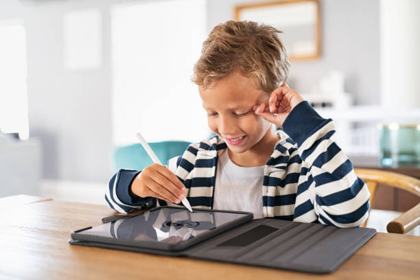 Boy drawing on digital tablet with pen Creative kid drawing on tablet using digital pen. Child using pen on tablet to draw and complete homework. Cute little boy using stylus on screen and drawing pictures at home. digitized pen photos stock pictures, royalty-free photos & images