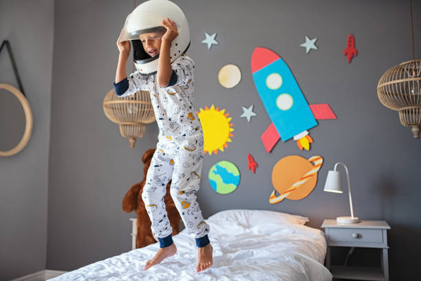 petit garçon heureux avec le casque d’astronaute sautant sur le bâti - rocket booster photos photos et images de collection