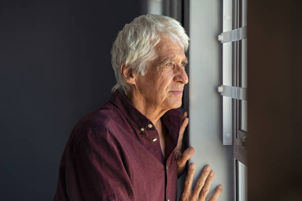 istock Lonely old man looking out the window 1256104369