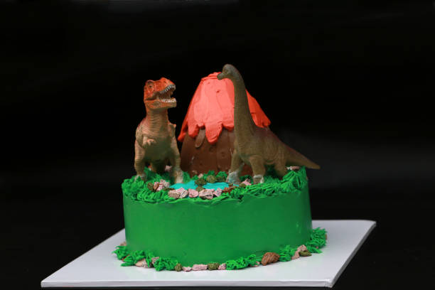 istock Two dinosaur dolls decorate on a volcanic cake and green forest. 1256104761