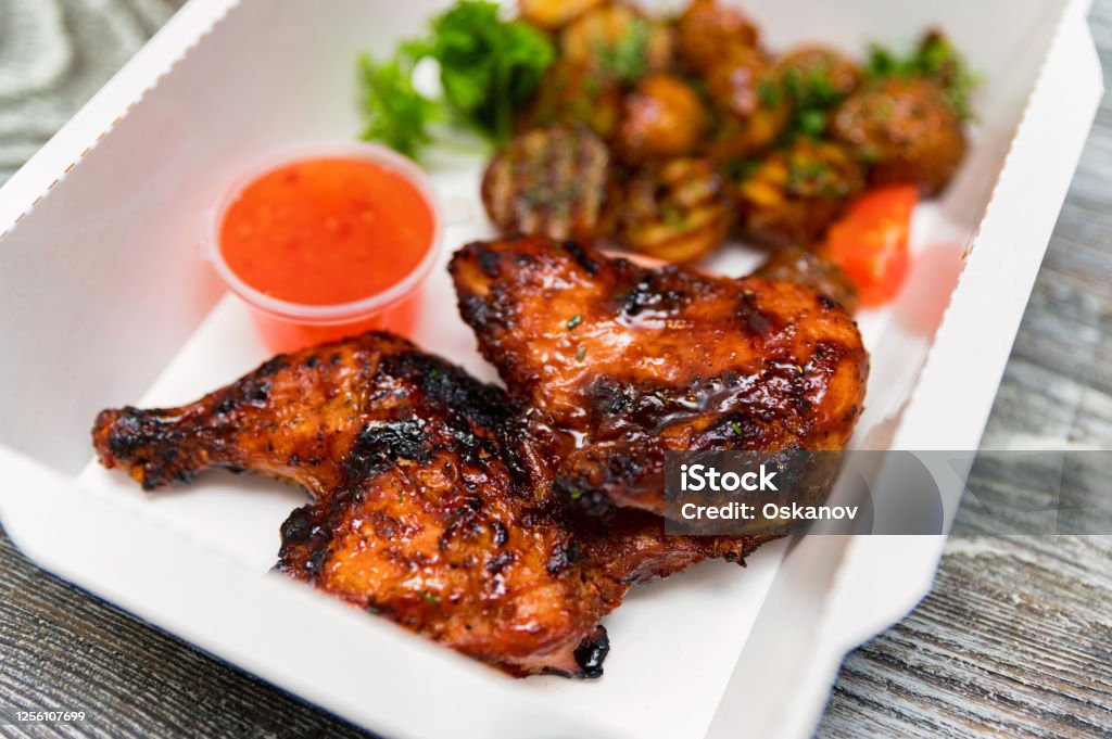 Caramelized BBQ chicken leg quarters with home-made fried potato. Food to go Caramelized BBQ chicken leg quarters or thigh with home-made fried potato prepared in lunch box. Delivery food concept Grilled Chicken Stock Photo