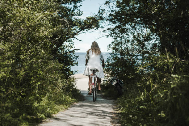 Young woman biking towards ocean