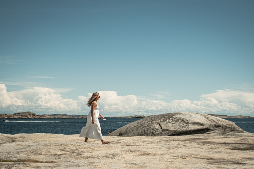 View of woman walking on rock by ocean in Hvasser, Norway.