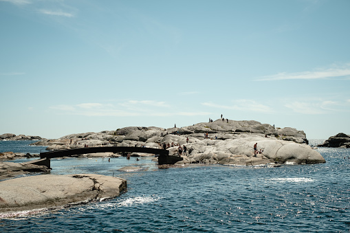View of bridge over rocks by ocean in Norway.