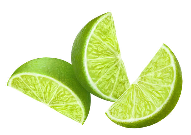 deliciosas rodajas de lima de cerca sobre blanco - limones verdes fotografías e imágenes de stock
