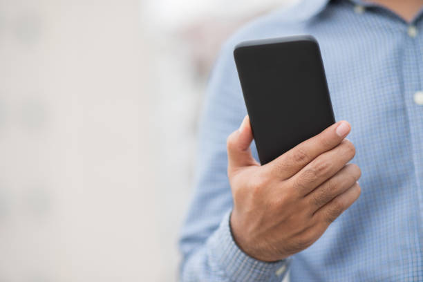 istock Close up male hands holding using black smartphone on city background. 1256109632